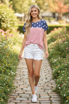 Navy star and red stripe Americana combo top candid walking — blonde model park path white denim shorts white sneakers lifestyle