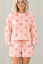 Close-up of pink lounge set with coral polka dots, solid pullover hem band and matching drawstring shorts