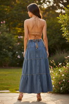 Back view of Risen denim tiered maxi skirt showing elastic waistband, 3 tiered panels with topstitched seams, and full A-line flare to ankle