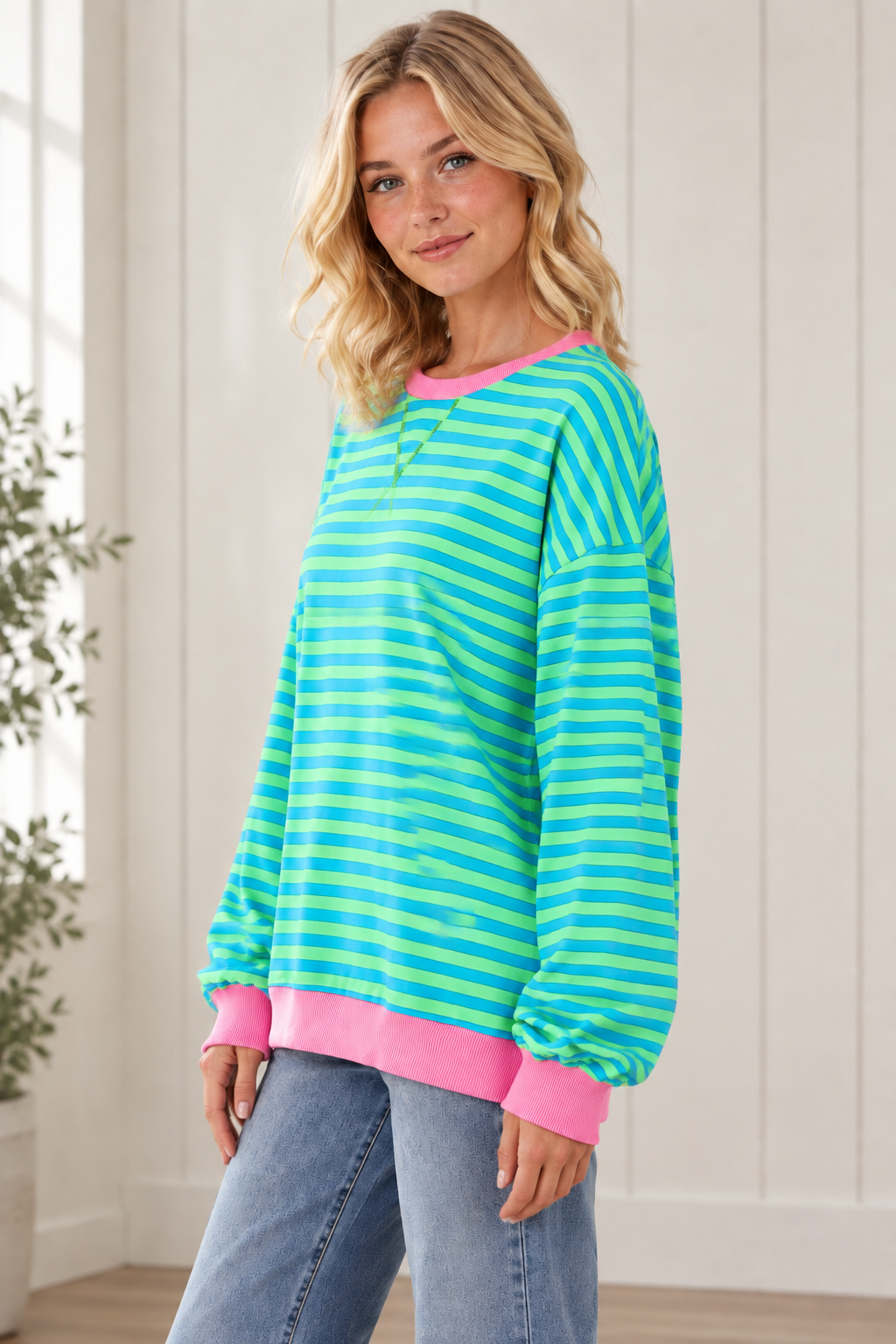 Side view of relaxed striped pullover showing dropped shoulders, loose sleeves and pink contrast trim.