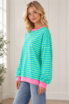 Side view of relaxed striped pullover showing dropped shoulders, loose sleeves and pink contrast trim.