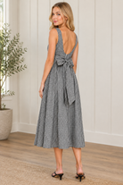 Back view of black and white gingham midi dress showing open scoop back and waist level self tie bow