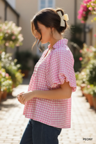 Side profile of Umgee pink gingham smocked yoke puff sleeve blouse — relaxed flowy silhouette styled with dark denim jeans