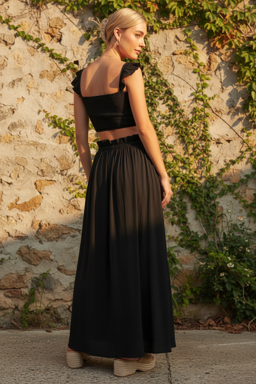 Black smocked crop top open back detail with ruffle sleeves and flowing black maxi skirt, back view, outdoor lifestyle photography