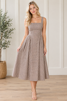Angled view of brown and cream gingham square neck dress with wide straps and midi hem