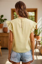 Back view of BiBi creamy yellow cotton ruffle eyelet blouse showing keyhole back closure and double-layer ruffle eyelet sleeves, styled with light wash denim shorts, shop Thread Bar Boutique