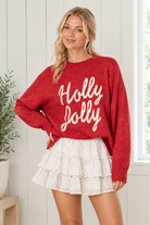 Red Holly Jolly Christmas sweater with ribbed crew neckline and cuffs, paired with an ivory mini skirt