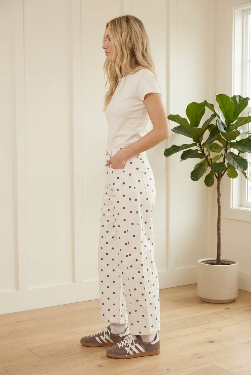 Ecru polka dot barrel jeans detail showing the button waist, front pockets, dark dot pattern and curved leg shape.