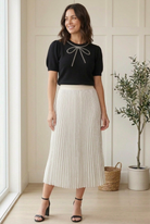 Side view of black beaded bow sweater showing puffed half sleeves and fitted sleeve cuffs.