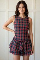Front view of the dark tartan plaid romper with red and green stripes, a sleeveless round neckline, fitted bodice, and layered ruffle shorts.
