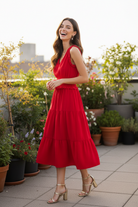 Cherry red smocked midi dress three quarter side view — flowy tiered skirt silhouette brunette model rooftop terrace lifestyle