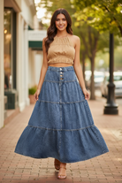 Brunette model walking in Risen acid-wash denim high-rise tiered maxi skirt, skirt flowing naturally showing 3-tier panel construction and A-line flare