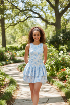 Sporty blue floral dress romper with double ruffled skirt in outdoor lifestyle setting