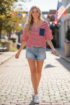 Red ivory stripe Americana waffle knit top candid walking lifestyle — blonde model denim cutoffs white sneakers festive outdoor setting