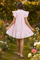 Umgee pink and white stripe seersucker ruffle dress back view showing dramatic double-layer butterfly sleeves, tiered ruffle hem, and A-line silhouette, outdoor garden lifestyle