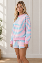 Three-quarter view of pink and aqua striped matching lounge outfit with oversized pullover and elastic-waist shorts