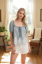 Lace denim top in front of living room window - standing
