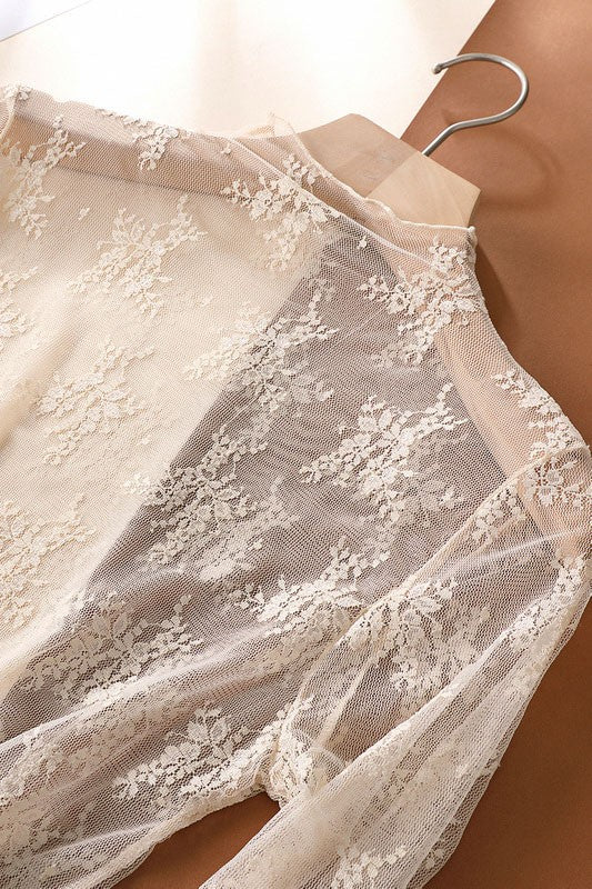 Close-up of a beige lace garment on a hanger against a neutral background