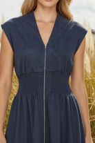 Close up of smocked waist front zip v neck stretch suede cap sleeve midi dress in denim blue