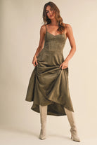 Woman wearing an olive suede bustier midi dress with adjustable straps and a flared skirt — trendy boutique fall outfit.