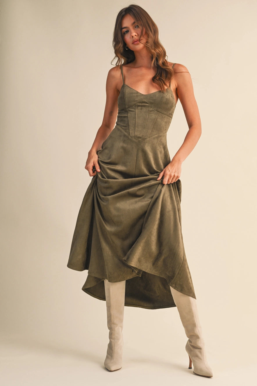 Woman wearing an olive suede bustier midi dress with adjustable straps and a flared skirt — trendy boutique fall outfit.