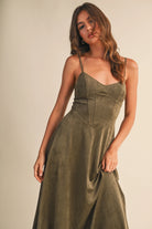 Woman wearing an olive suede bustier midi dress with adjustable straps and a flared skirt — trendy boutique fall outfit.