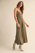Woman wearing an olive suede bustier midi dress with adjustable straps and a flared skirt — trendy boutique fall outfit.