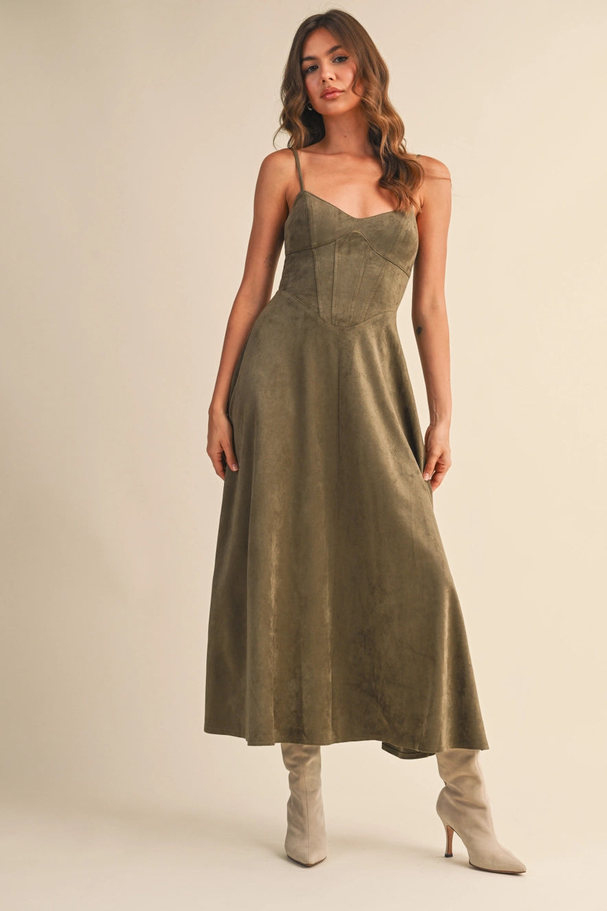 Woman wearing an olive suede bustier midi dress with adjustable straps and a flared skirt — trendy boutique fall outfit.