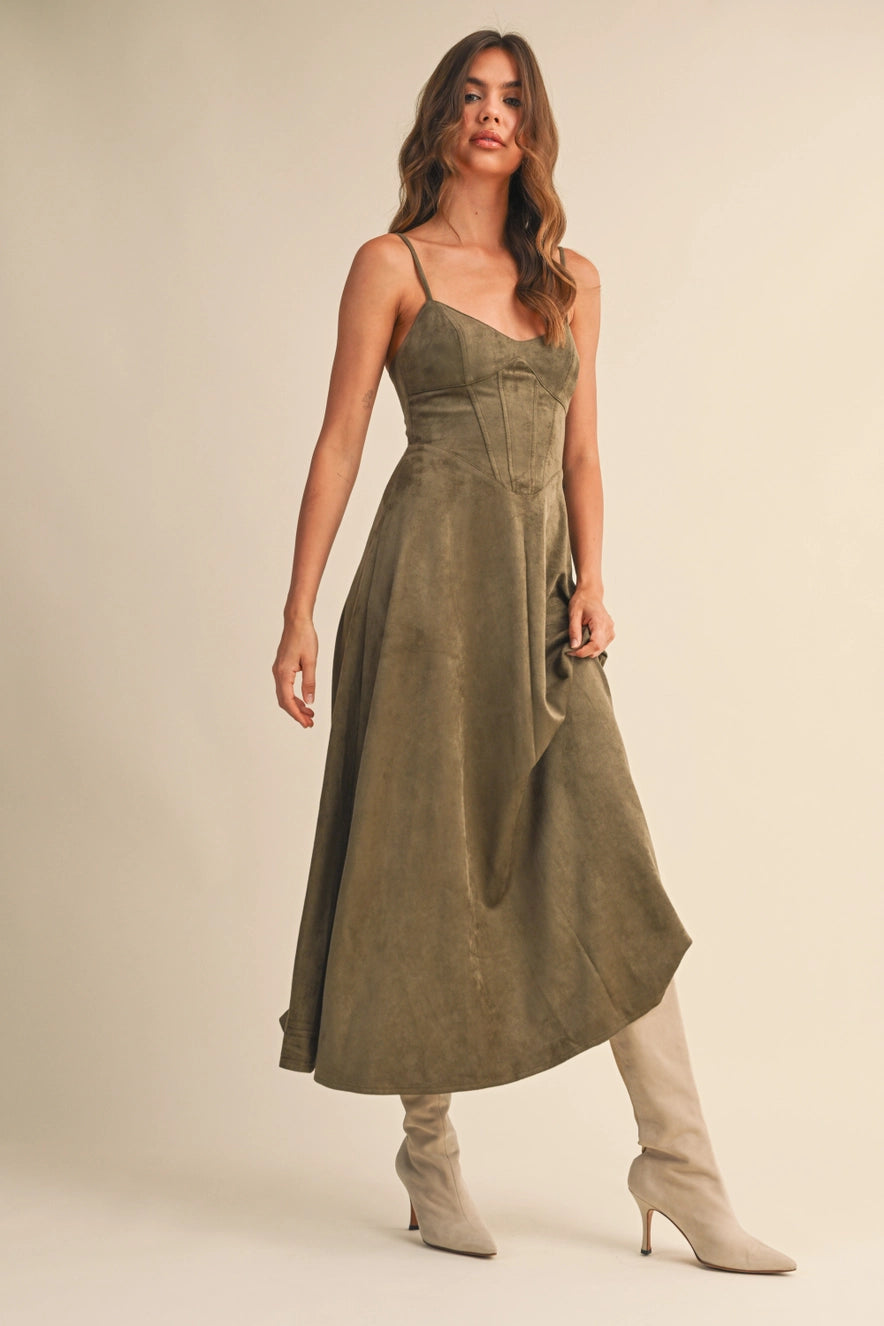 Woman wearing an olive suede bustier midi dress with adjustable straps and a flared skirt — trendy boutique fall outfit.
