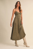 Woman wearing an olive suede bustier midi dress with adjustable straps and a flared skirt — trendy boutique fall outfit.