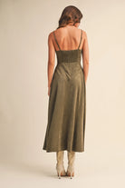 Woman wearing an olive suede bustier midi dress with adjustable straps and a flared skirt — trendy boutique fall outfit.