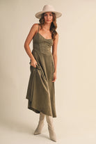 Woman wearing an olive suede bustier midi dress with adjustable straps and a flared skirt — trendy boutique fall outfit.