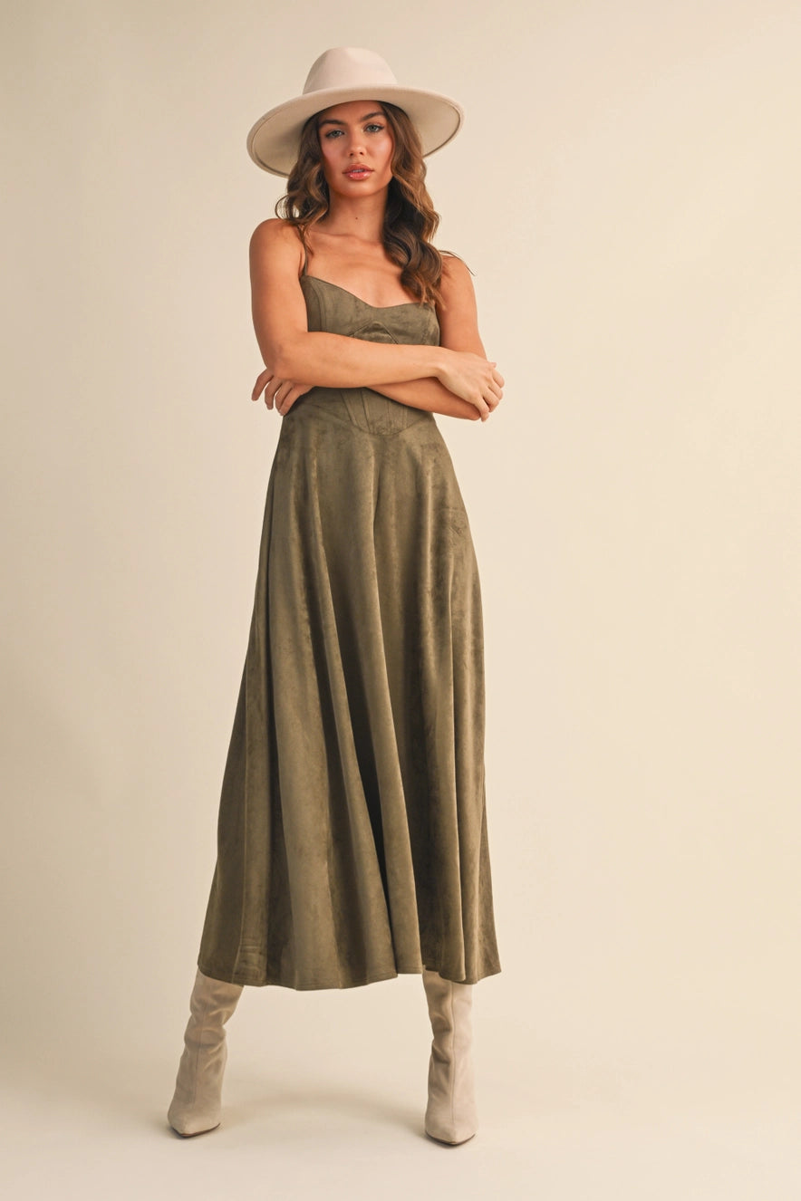 Woman wearing an olive suede bustier midi dress with adjustable straps and a flared skirt — trendy boutique fall outfit.