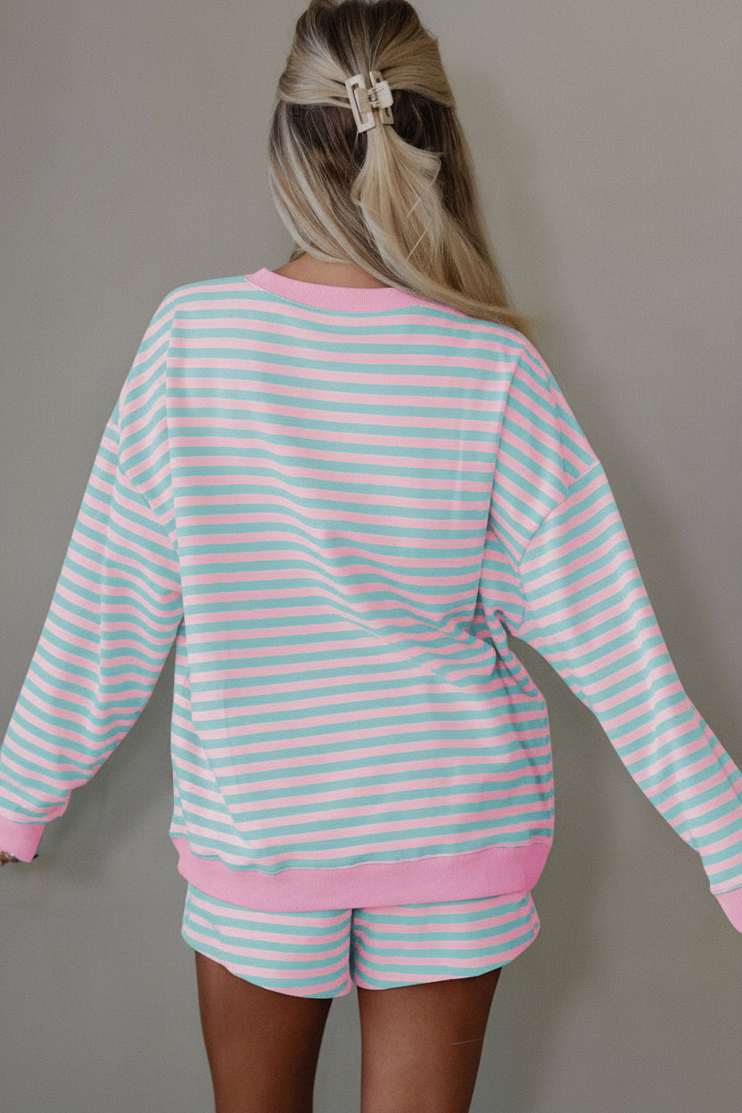 Person wearing a pink and light blue striped outfit with shorts on a plain background