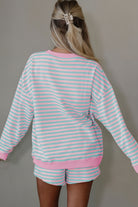 Person wearing a pink and light blue striped outfit with shorts on a plain background