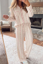 A woman wearing a matching long-sleeve pajama set with a cream base and pink floral vertical stripes