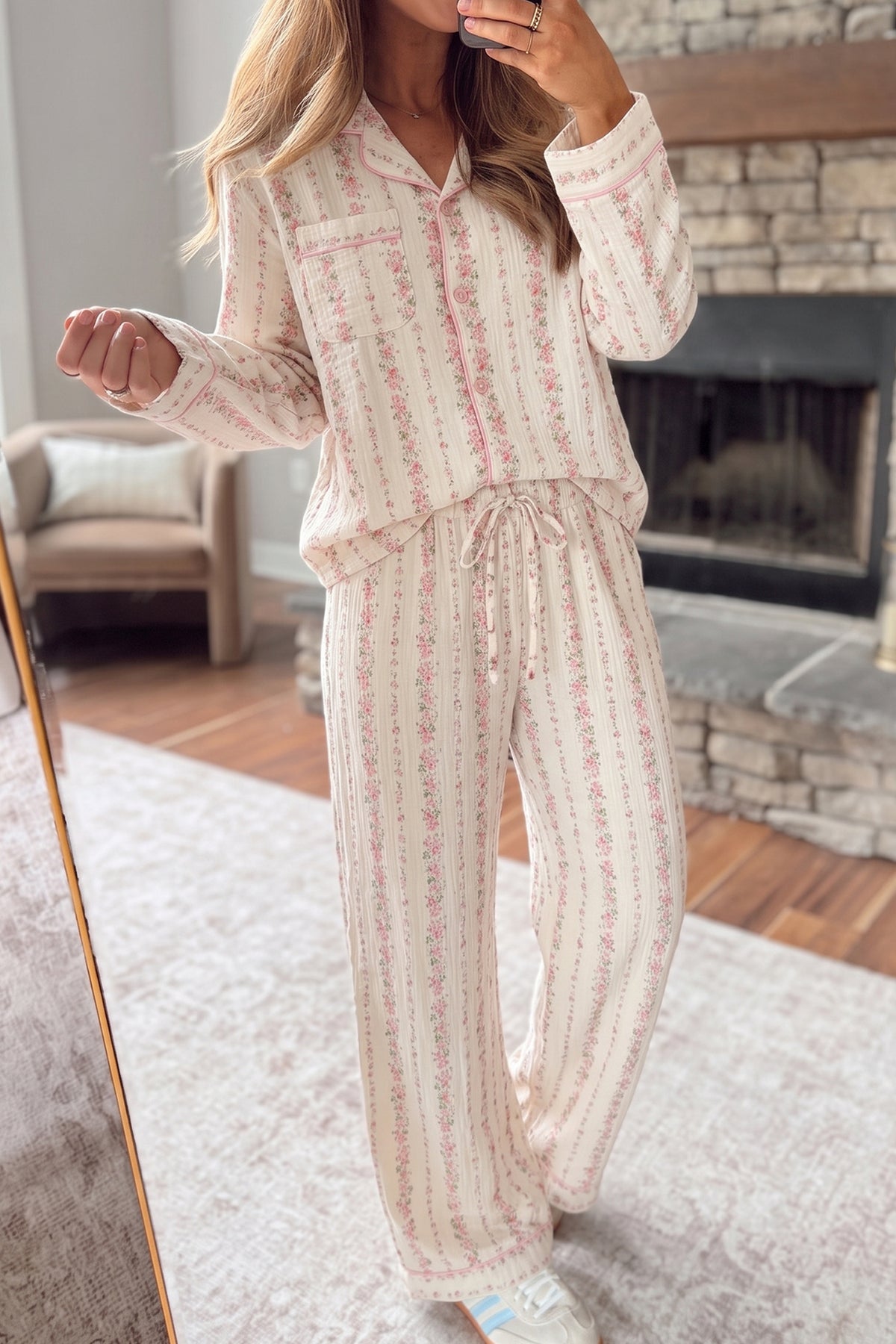 A woman wearing a matching long-sleeve pajama set with a cream base and pink floral vertical stripes
