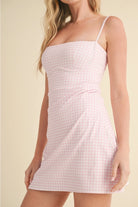 Model wearing a pink gingham athletic mini dress with built-in shorts