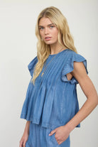 Side profile of ruffle sleeve denim top showing relaxed fit and ruffle hem pleats