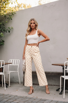 Cream wide-leg pants with allover polka dot print, featuring elastic back waistband and button front closure