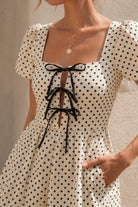 Woman wearing a polka dot romper dress with a bow detail 