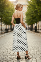 Black strapless polka dot midi dress with a sleek tube fit, combining structured and soft fabric for a flattering shape, complete with side pockets and a lined skirt