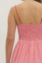 Model wearing a sweetheart gingham maxi dress with adjustable straps, bow details, smocked back, and side pockets in a romantic gingham print, perfect for Valentine’s Day and spring occasions.