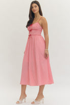 Model wearing a sweetheart gingham maxi dress with adjustable straps, bow details, smocked back, and side pockets in a romantic gingham print, perfect for Valentine’s Day and spring occasions.