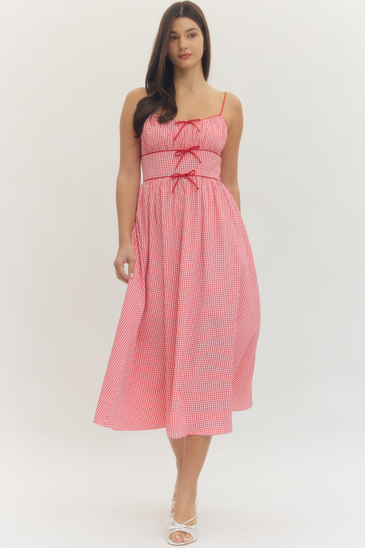 Model wearing a sweetheart gingham maxi dress with adjustable straps, bow details, smocked back, and side pockets in a romantic gingham print, perfect for Valentine’s Day and spring occasions.