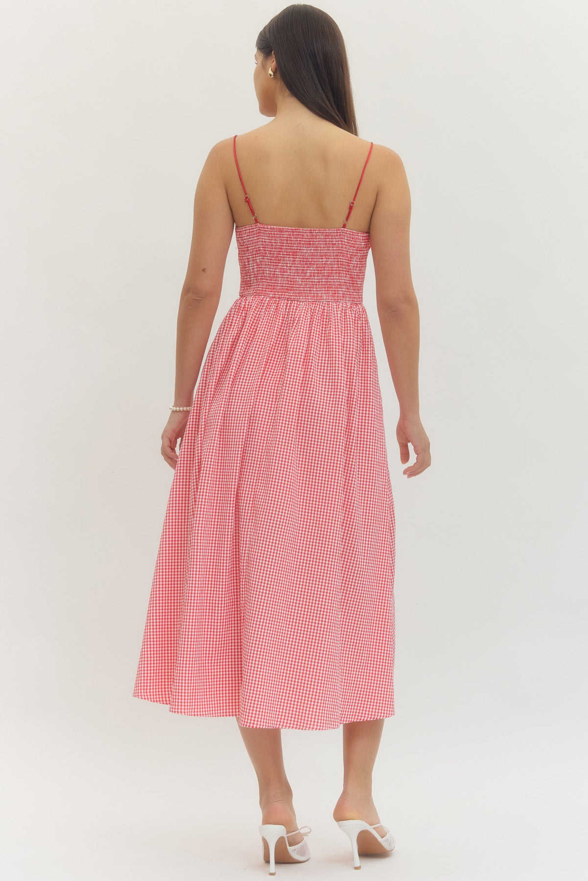 Model wearing a sweetheart gingham maxi dress with adjustable straps, bow details, smocked back, and side pockets in a romantic gingham print, perfect for Valentine’s Day and spring occasions.