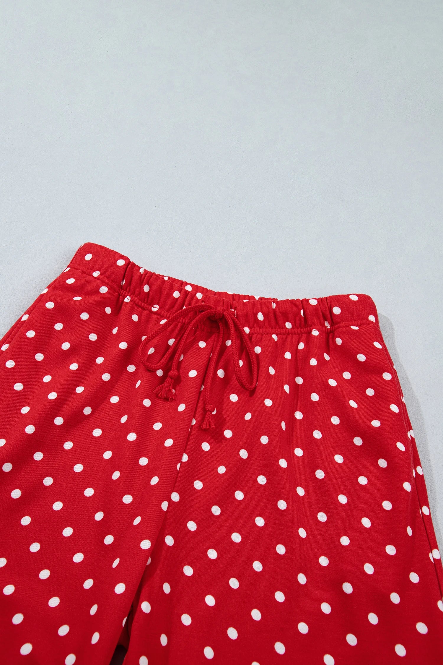Red drawstring shorts with a white polka dot pattern, photographed against a light gray background.