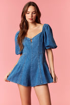 Woman wearing a game day denim romper with bubble sleeves and pleated detail with tie back
