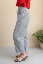 Side profile close-up of striped barrel pants — curved seam panel detail, tapered ankle hem, elasticized drawstring waist