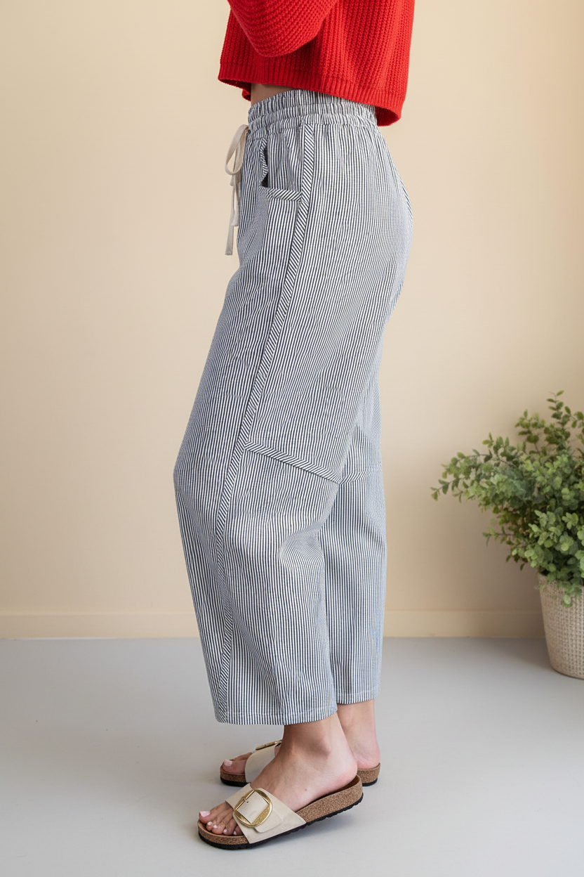 Side profile close-up of striped barrel pants — curved seam panel detail, tapered ankle hem, elasticized drawstring waist